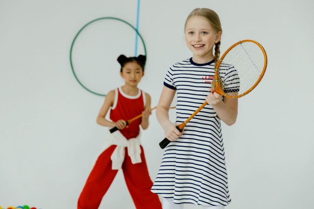 Two children enjoy indoor racquet games with smiles and energy.